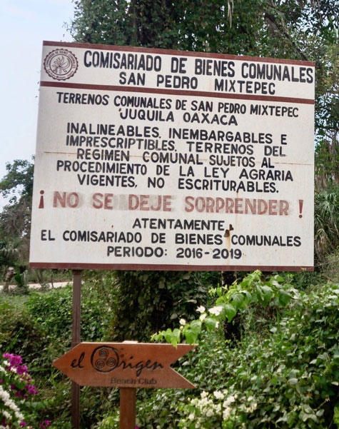 Highway warning to potential buyers of land in Palmarito by the Bienes Comunales of San Pedro Mixtepec. It says the land cannot be legally owned with a title since it is part of the communal land of San Pedro and falls under the jurisdiction of the agrarian law.